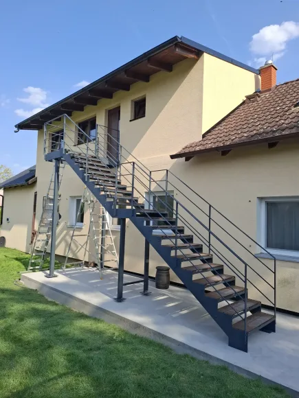 Antracitové venkovní schodiště s dřevěnými stupni k patru