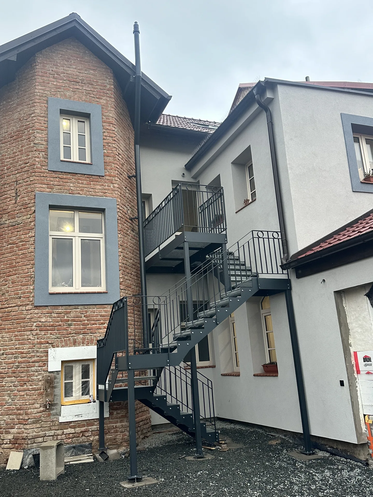 Antracitové venkovní schodiště s podestami mezi patry historického domu