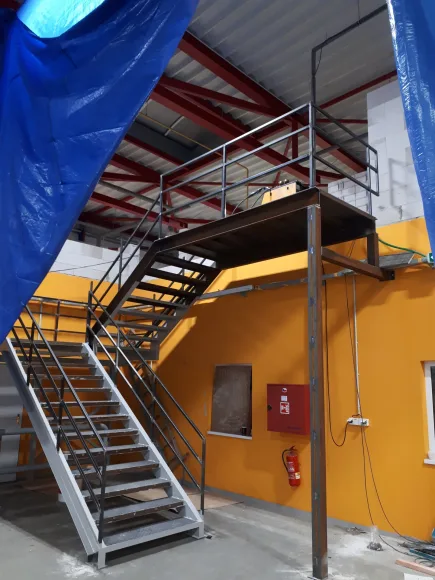 Ocelové industriální schodiště k plošině v hale
