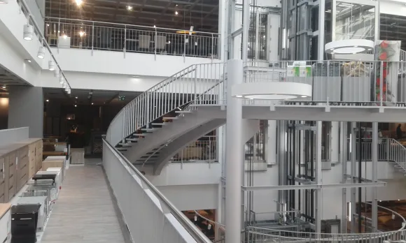 Zakřivené ocelové schodiště v obchodním centru s výtahovou šachtou