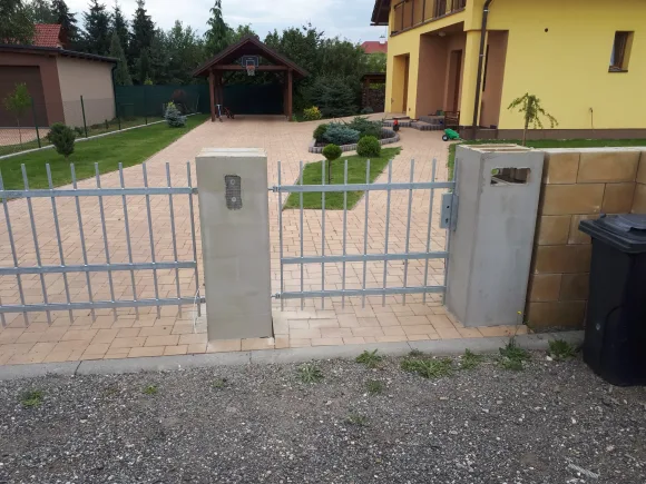 Dvoukřídlá kovová vrata mezi zděnými sloupky
