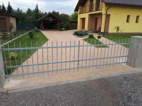 Posuvná pozinkovaná brána s tyčovou výplní u vjezdu