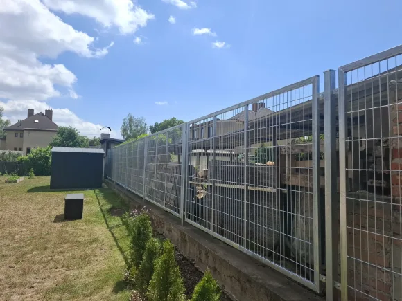 Pozinkovaný plot s mřížovou výplní na zídce