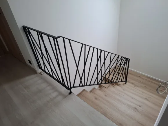 Černé zábradlí s originálním diagonálním vzorem u schodiště