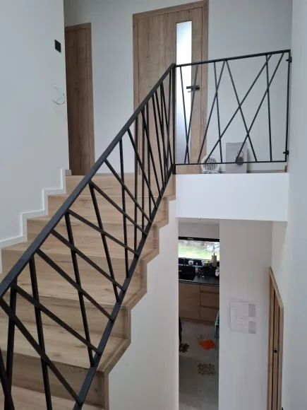 Celkový pohled na dřevěné schodiště s originálním diagonálním zábradlím