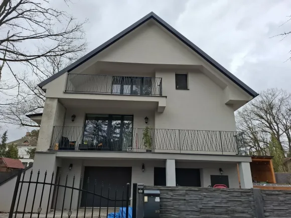 Zábradlí balkonů s diagonálním vzorem na fasádě vily