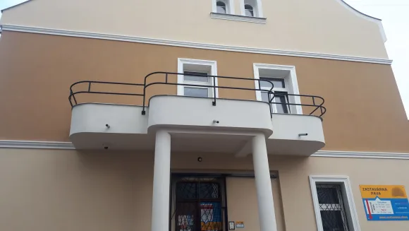 Černé kovové zábradlí zaobleného balkonu na fasádě